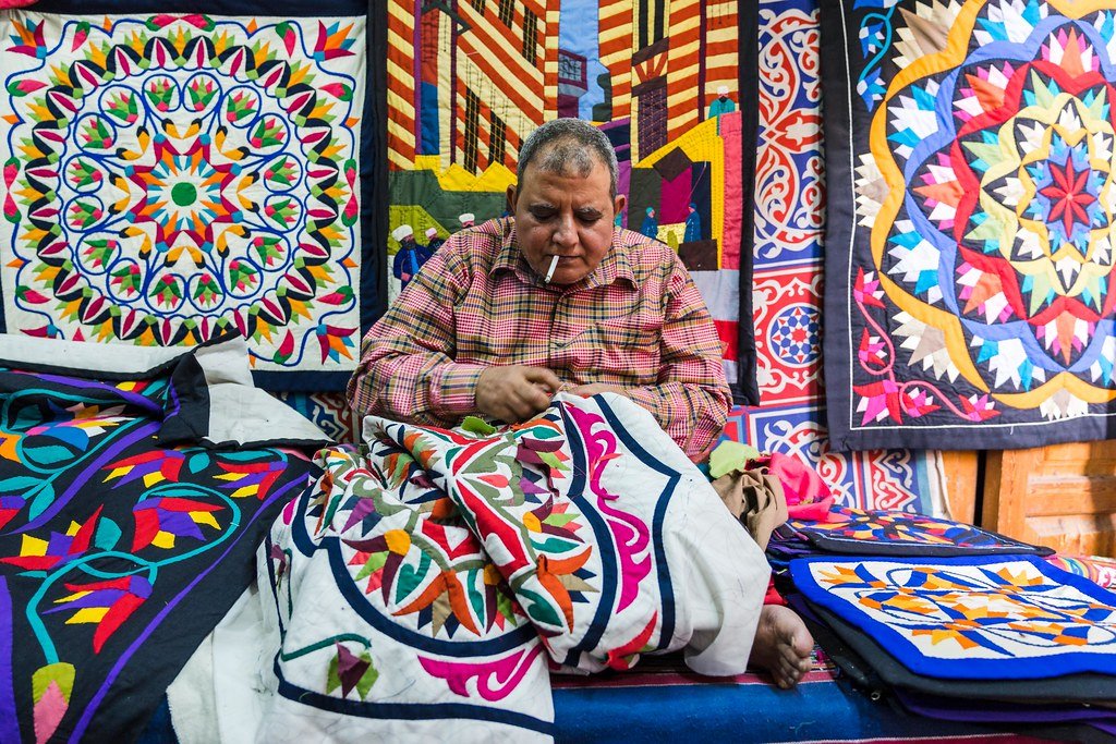 حرفي مصري يعمل على تطريز قطعة من الخيامية التقليدية، مستخدمًا الإبرة والخيط لتشكيل زخارف مستوحاة من الفن الشعبي المصري. حقوق الطبع والنشر: Christopher Wilton-Steer